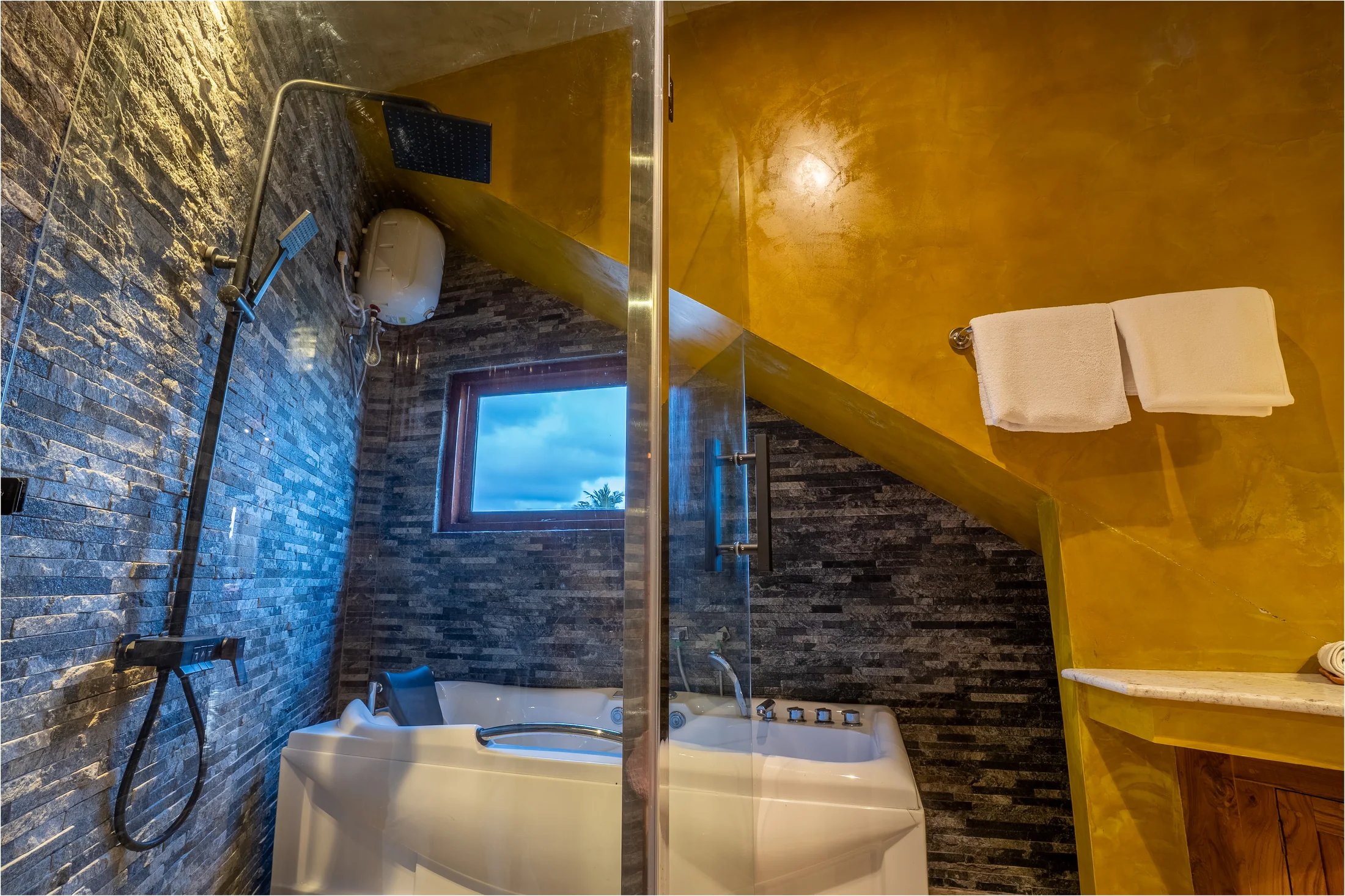 Glass shower, stone wall and deep bath in the private en-suite