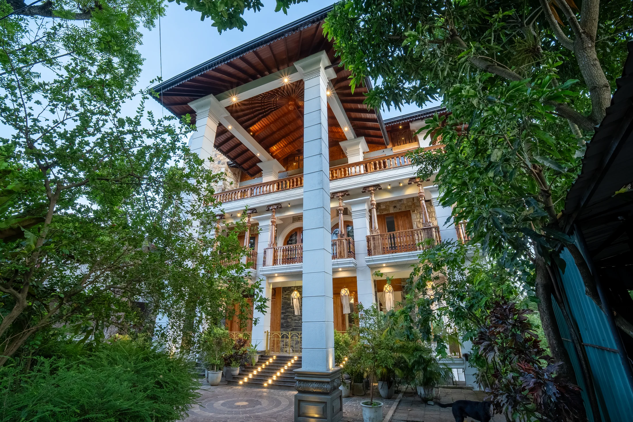 Full-height view of the multi-level residence framed by tropical trees