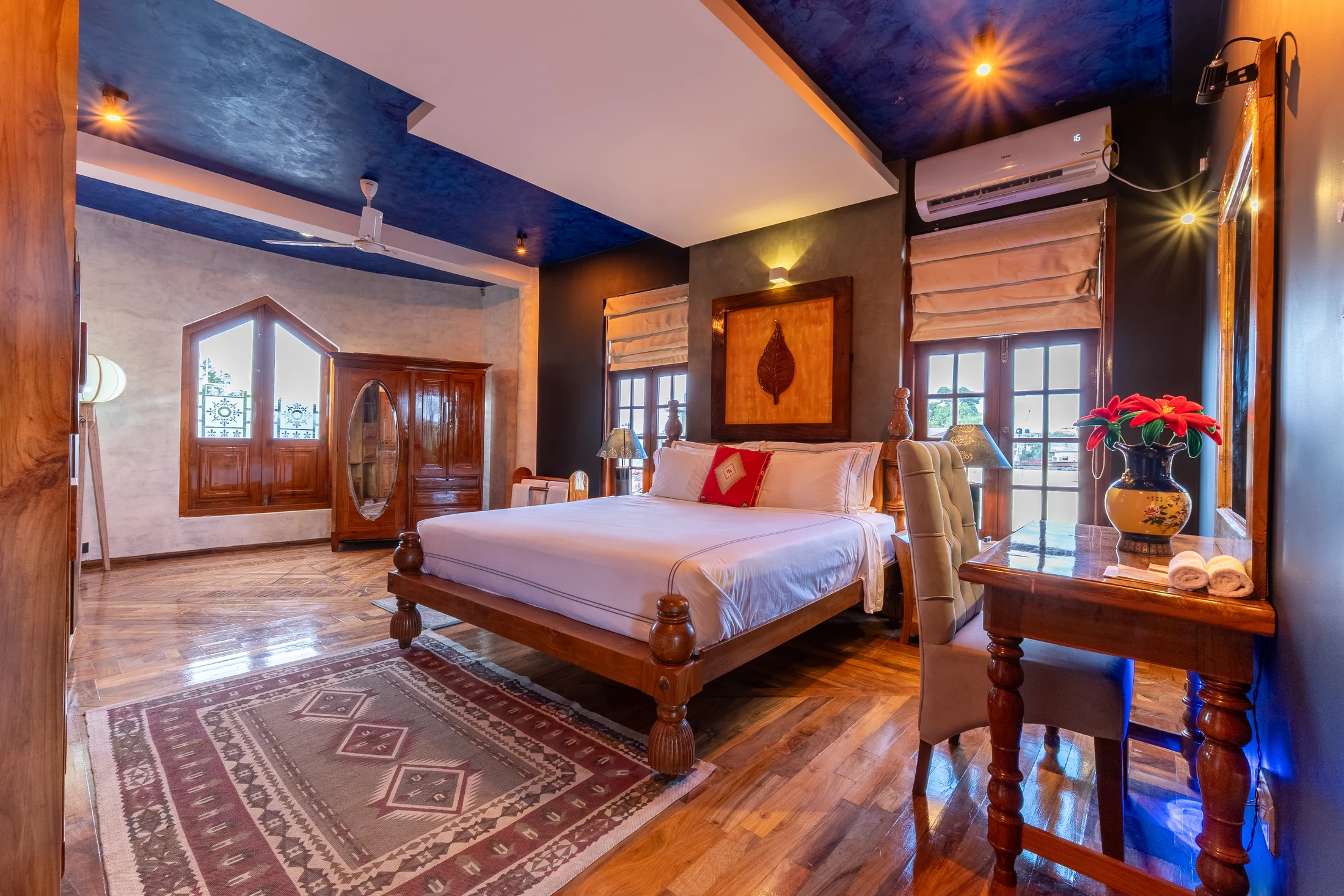 Full bedroom with carved timber bed, dressing table, windows and polished floor