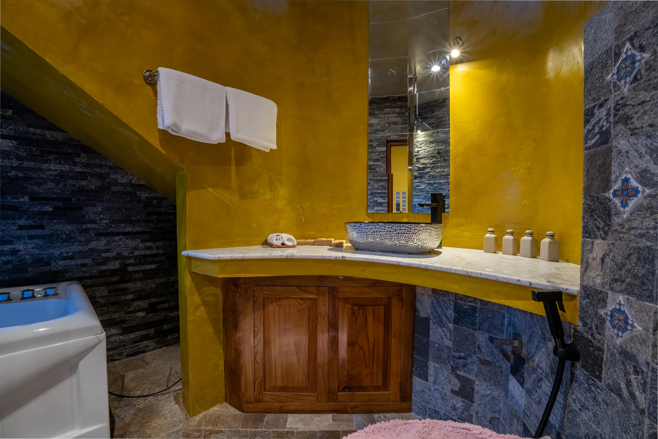 Private en-suite vanity with stone counter, timber cabinet and golden walls