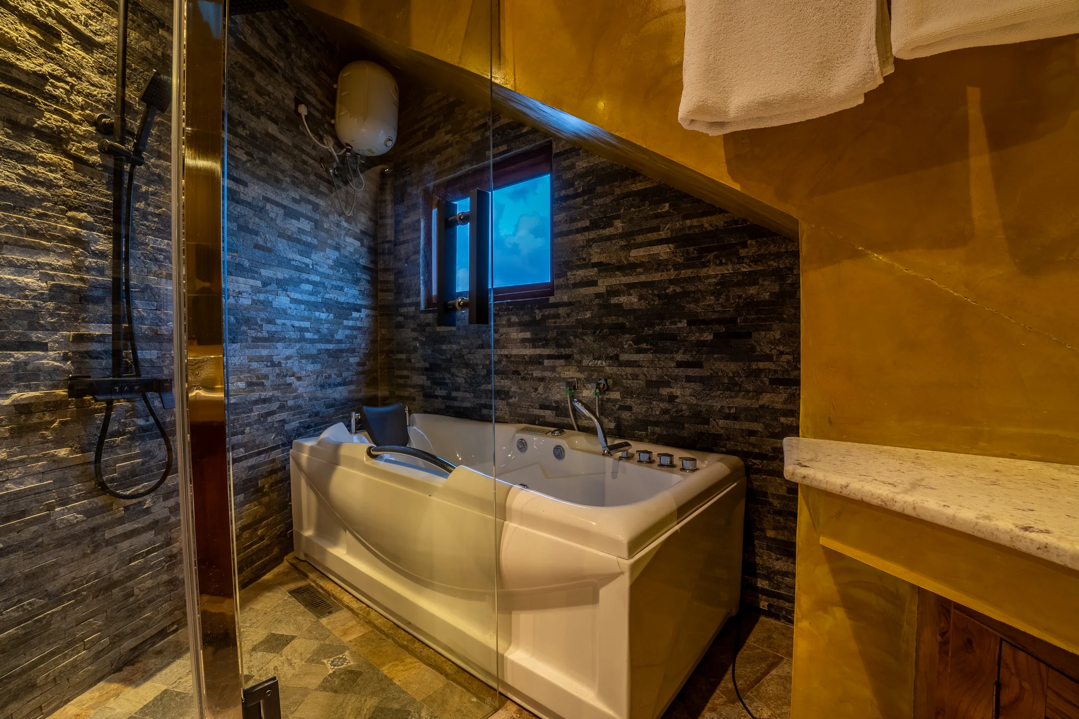Stone-finished bathroom wall, timber door and upholstered stool
