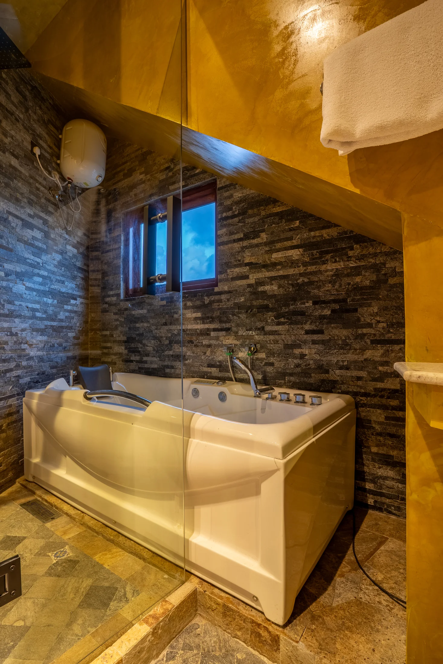 Deep bath framed by dark stone tiles and warm golden surfaces