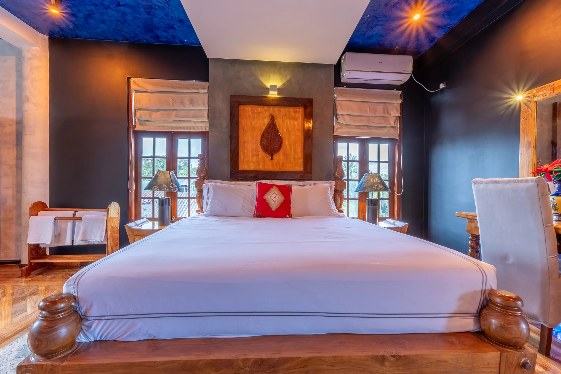 Front view of the carved timber bed between tall bedroom windows
