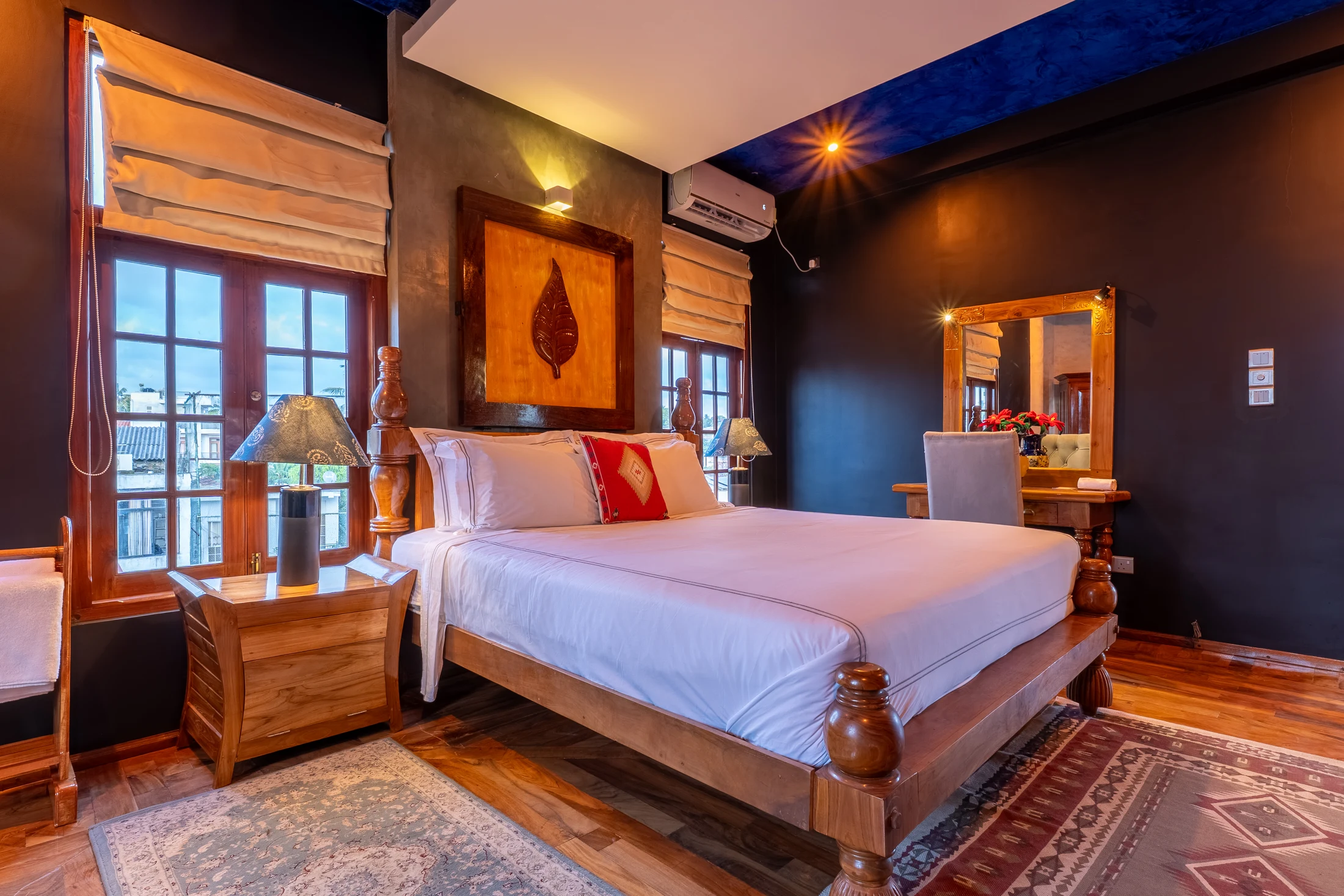 Wide bedroom view with the bed, windows, rug and timber doorway