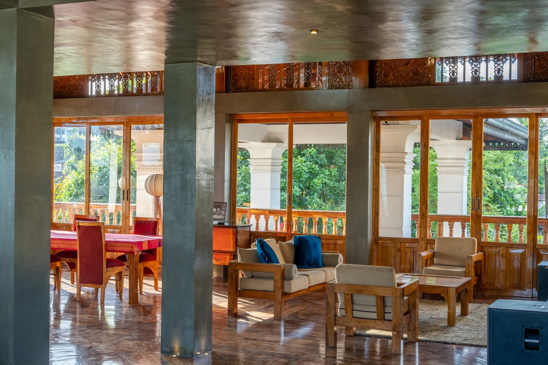 Full living and dining space with timber seating, columns and garden-facing windows